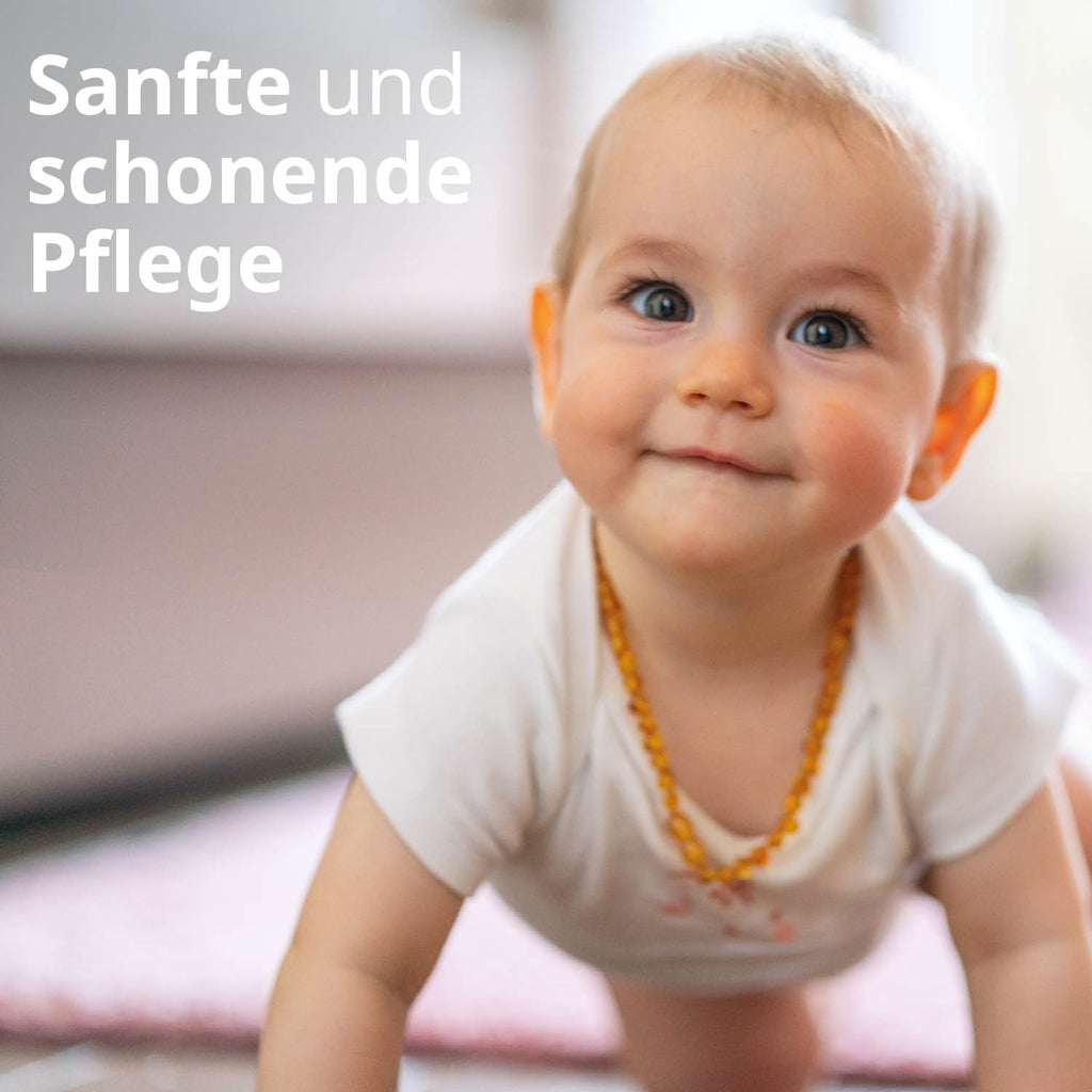 Ein kleines Baby schaut nach vorne, lächelt. Text: Sanfte und schonende Pflege
